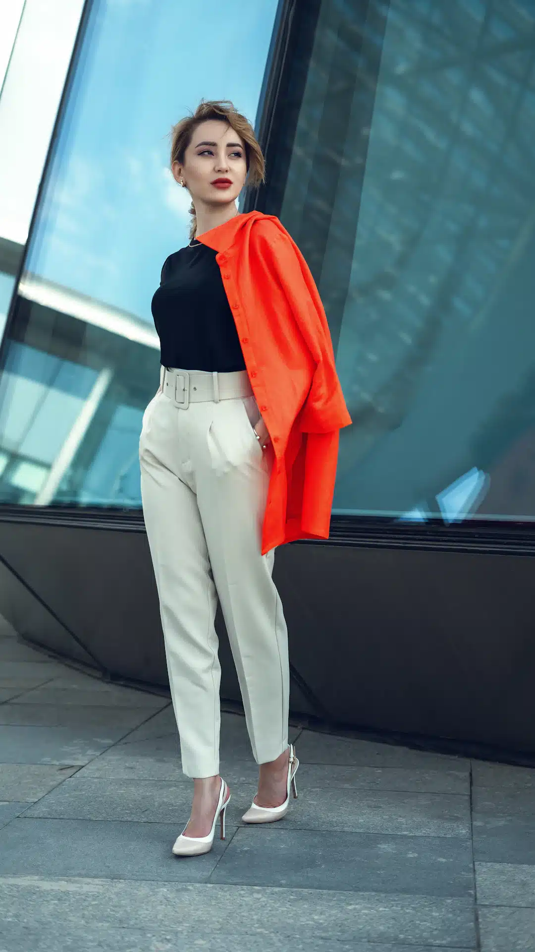 a woman standing on a sidewalk in front of a building