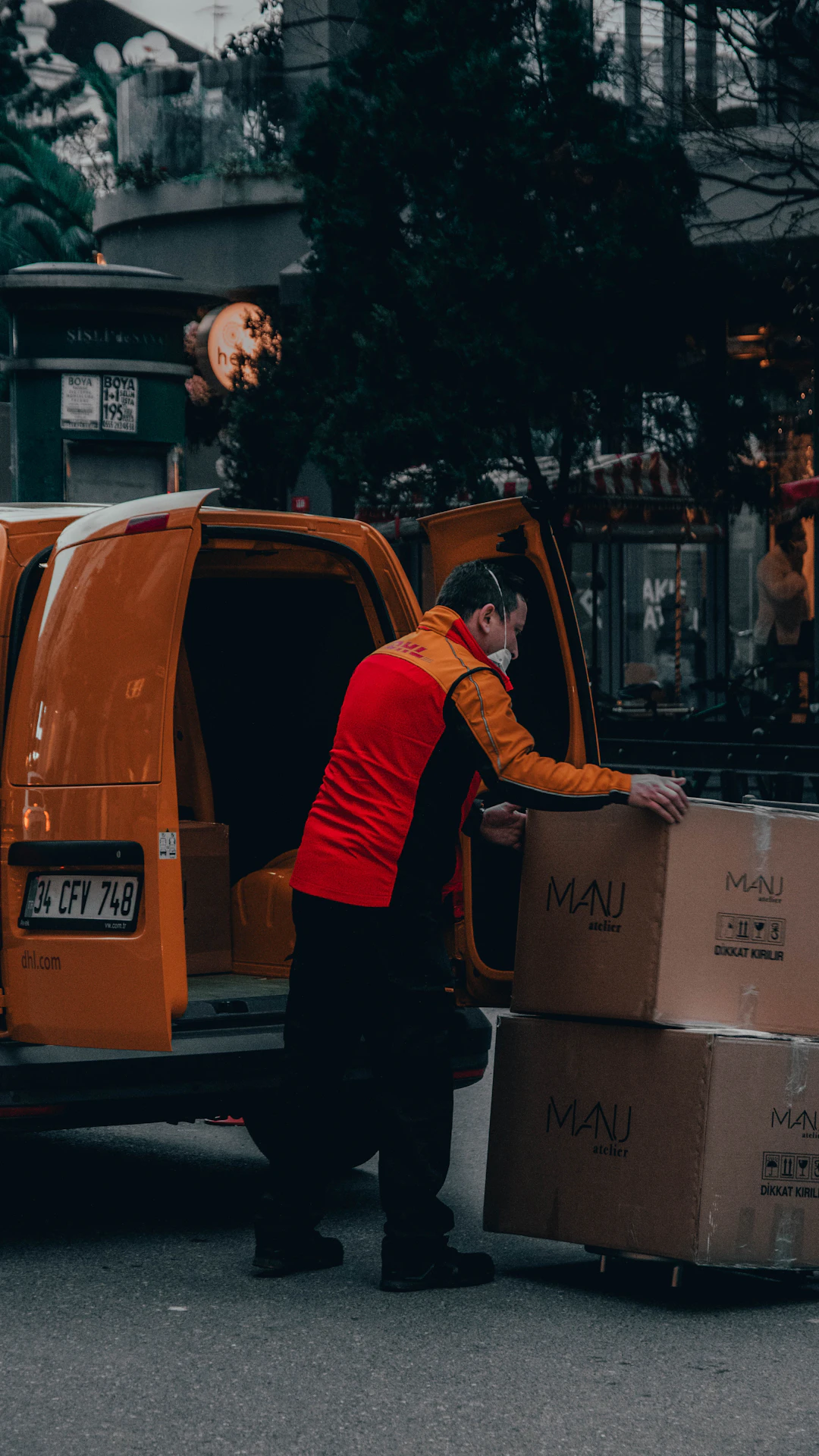 man in red jacket standing beside orange van during daytime