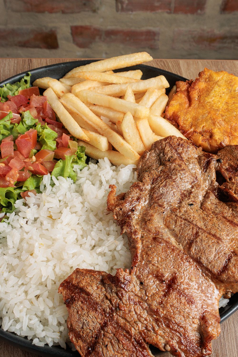 Delectable Colombian Bandeja Paisa featuring grilled meat, rice, fries, salad, and patacones.