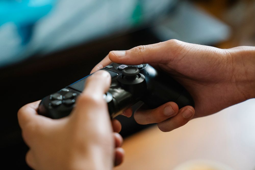 Crop unrecognizable man with modern gamepad playing video game while having free time at home